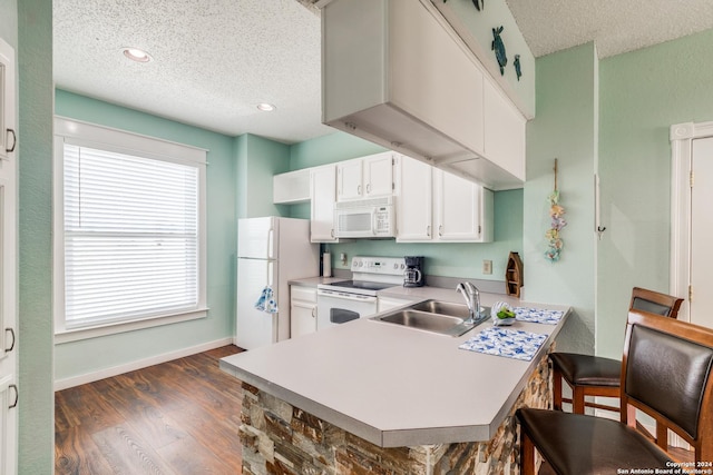 kitchen with a kitchen bar, sink, kitchen peninsula, white appliances, and white cabinets