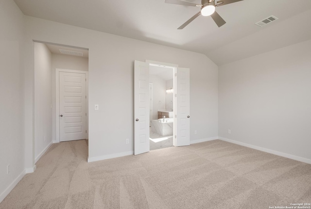 unfurnished bedroom featuring vaulted ceiling, light colored carpet, and ensuite bathroom