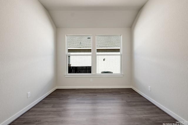 spare room featuring vaulted ceiling and dark hardwood / wood-style flooring