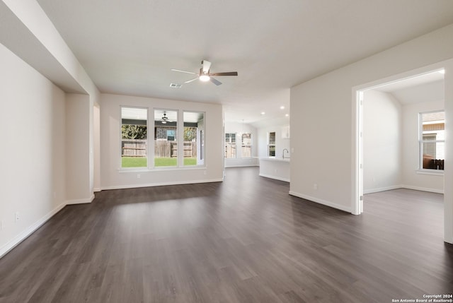 unfurnished living room featuring dark wood-type flooring and ceiling fan