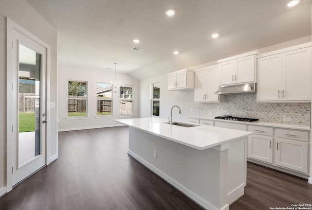 kitchen with sink, white cabinetry, hanging light fixtures, stainless steel gas cooktop, and a center island with sink