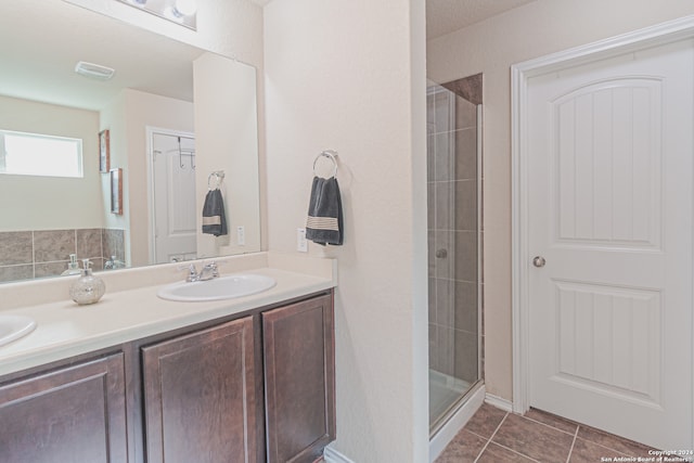 bathroom featuring a shower with door, double vanity, and tile patterned floors