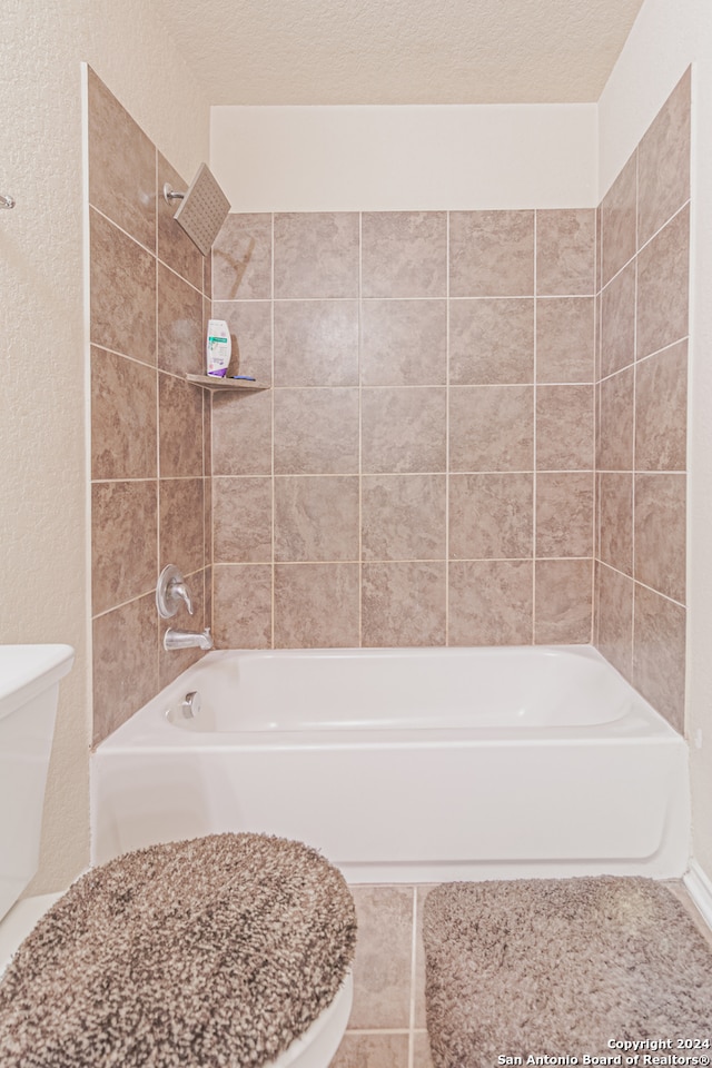 bathroom with tiled shower / bath, a textured ceiling, and toilet