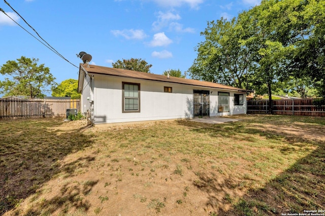 back of property featuring cooling unit and a lawn