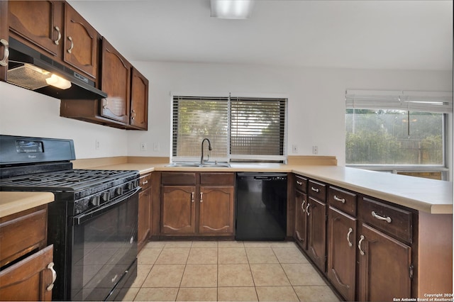 kitchen with light tile patterned floors, kitchen peninsula, sink, and black appliances