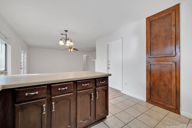 kitchen featuring light tile patterned flooring, dark brown cabinetry, decorative light fixtures, and a chandelier