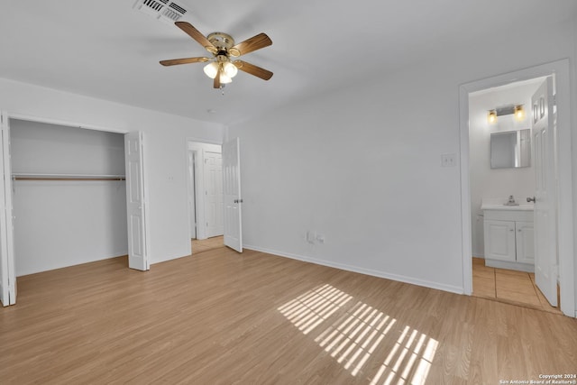 unfurnished bedroom featuring sink, light hardwood / wood-style flooring, ceiling fan, ensuite bathroom, and a closet