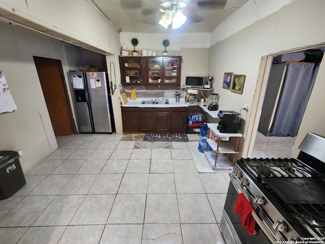 kitchen featuring appliances with stainless steel finishes, sink, ceiling fan, light tile patterned floors, and dark brown cabinets