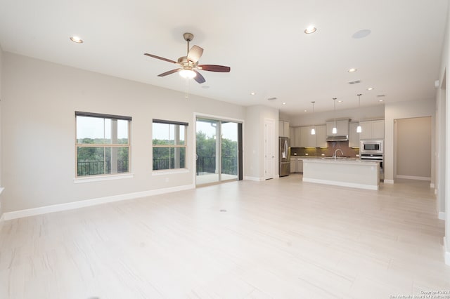 unfurnished living room featuring sink and ceiling fan