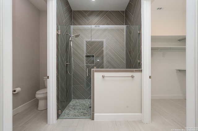 bathroom with tiled shower, tile patterned floors, and toilet