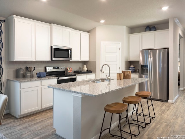 kitchen with sink, white cabinetry, appliances with stainless steel finishes, and a kitchen island with sink