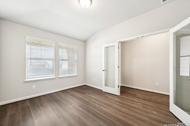 unfurnished bedroom featuring french doors, dark hardwood / wood-style flooring, and vaulted ceiling