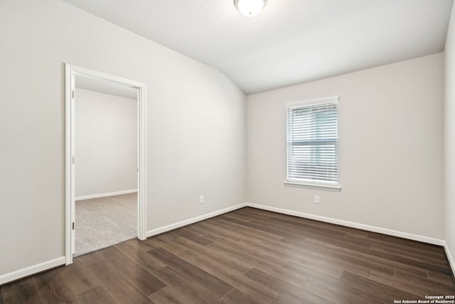 spare room with lofted ceiling and dark hardwood / wood-style flooring