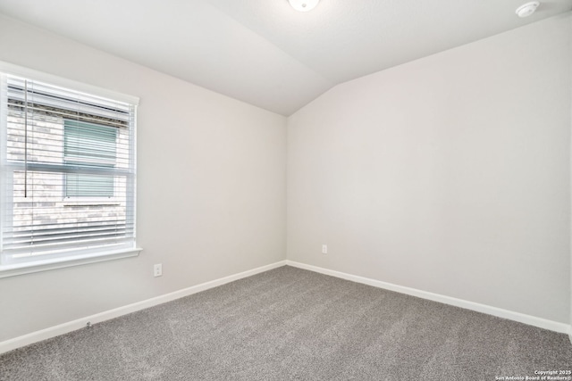 carpeted spare room featuring vaulted ceiling