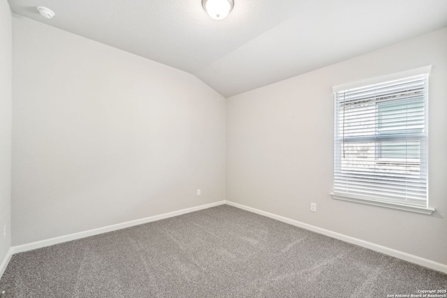 spare room featuring vaulted ceiling and carpet