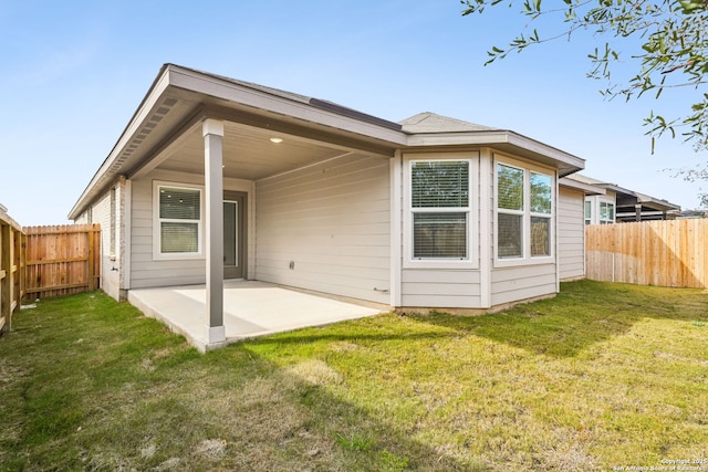 rear view of house featuring a lawn and a patio