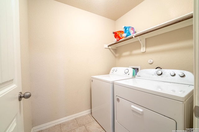 clothes washing area with light tile patterned floors, a textured ceiling, and washing machine and clothes dryer