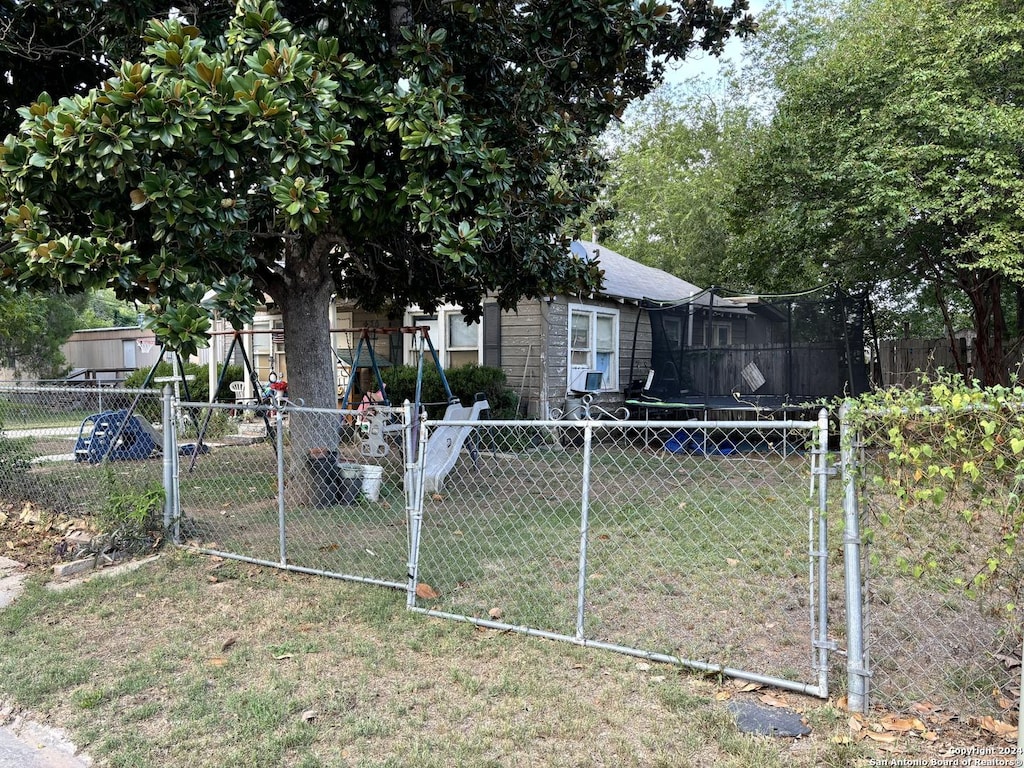 view of front of house with fence private yard, a trampoline, a gate, and a front yard