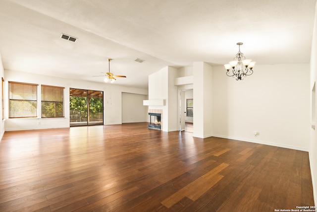 unfurnished living room featuring a tiled fireplace, ceiling fan with notable chandelier, dark wood-type flooring, and lofted ceiling