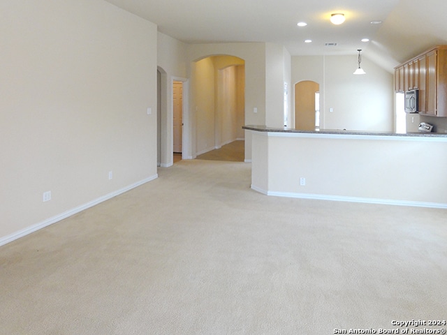 unfurnished living room with light carpet and vaulted ceiling