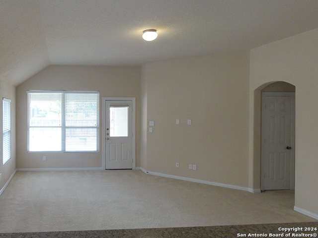 carpeted spare room with vaulted ceiling