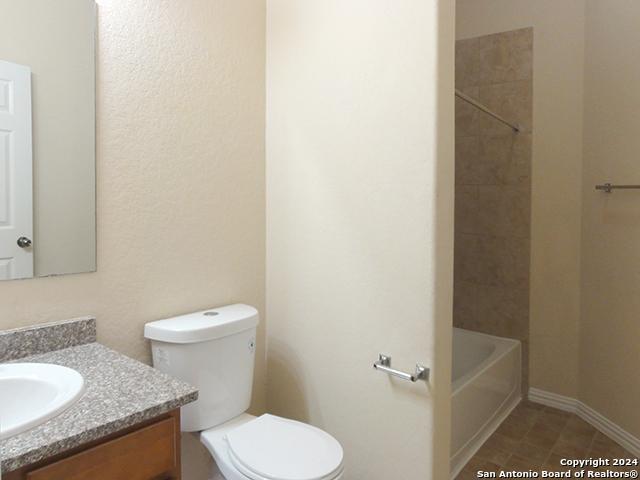 full bathroom featuring tile patterned floors, vanity, tiled shower / bath, and toilet