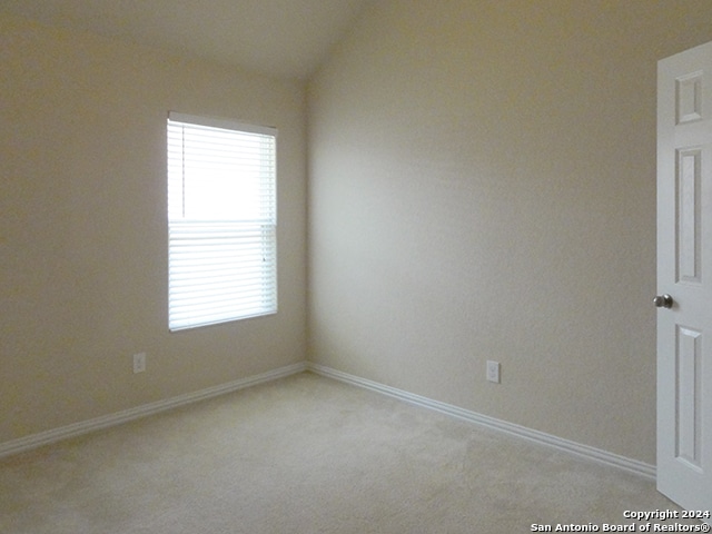 unfurnished room with plenty of natural light, light carpet, and vaulted ceiling