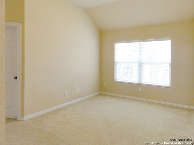 unfurnished room featuring lofted ceiling and light carpet