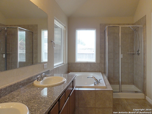 bathroom featuring shower with separate bathtub, tile patterned flooring, double vanity, and lofted ceiling