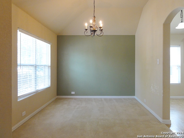 empty room with lofted ceiling, carpet flooring, and a chandelier