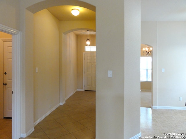 hallway featuring tile patterned flooring and a chandelier