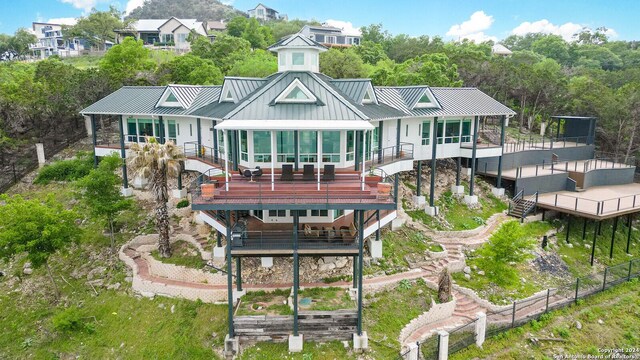 rear view of property with metal roof, a deck, stairs, and a standing seam roof