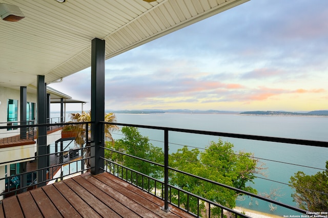 balcony at dusk featuring a water view