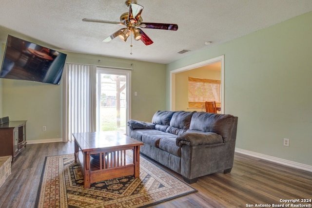 living room featuring dark hardwood / wood-style floors, ceiling fan, and a textured ceiling