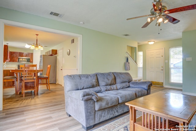 living room with a textured ceiling, sink, ceiling fan with notable chandelier, and light wood-type flooring