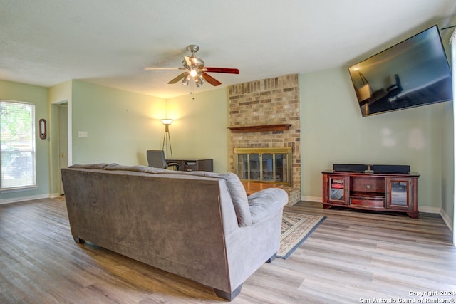 living room featuring hardwood / wood-style flooring, a brick fireplace, brick wall, and ceiling fan