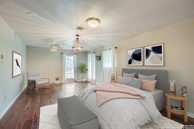 bedroom with ceiling fan with notable chandelier, dark hardwood / wood-style floors, and a textured ceiling