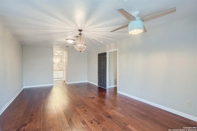 spare room with dark hardwood / wood-style floors and ceiling fan with notable chandelier