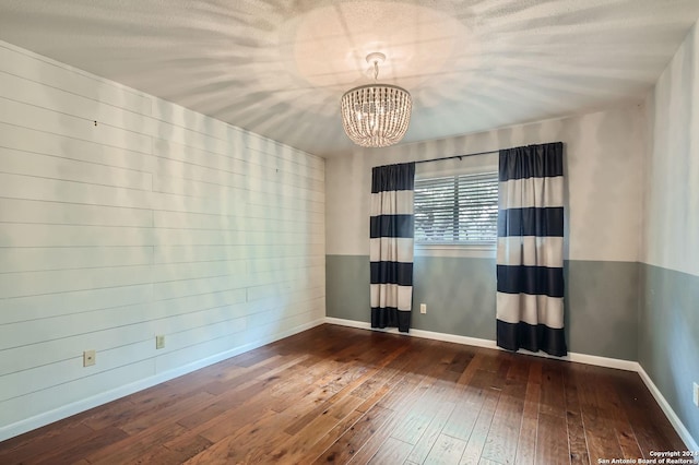 empty room featuring dark hardwood / wood-style flooring and a chandelier