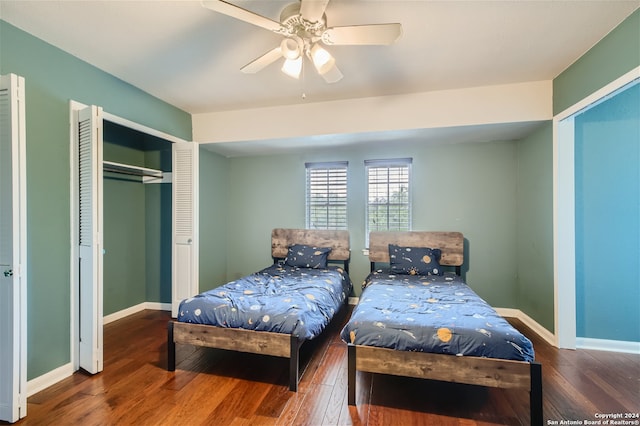 bedroom with hardwood / wood-style floors, two closets, and ceiling fan