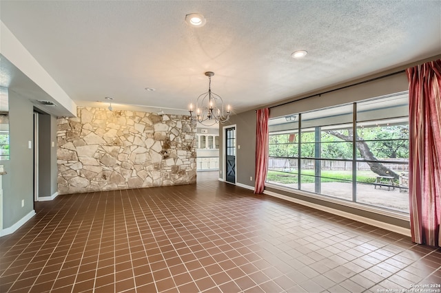 unfurnished room with a textured ceiling and a chandelier