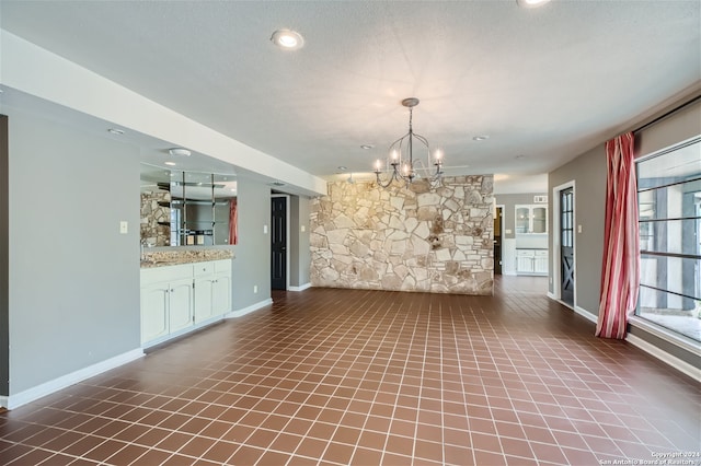 unfurnished dining area with a textured ceiling and a chandelier