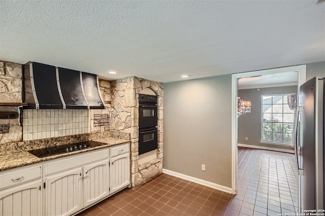 kitchen featuring extractor fan, black appliances, a textured ceiling, light stone countertops, and backsplash