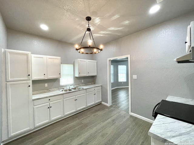 kitchen with decorative light fixtures, white cabinetry, hardwood / wood-style flooring, sink, and an inviting chandelier