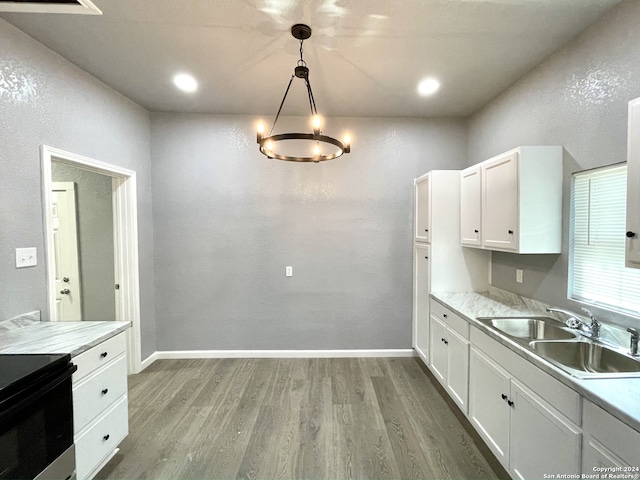 kitchen featuring white cabinetry, wood-type flooring, decorative light fixtures, and sink