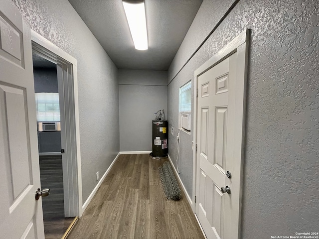 corridor with water heater, hardwood / wood-style floors, and cooling unit