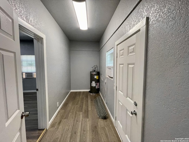 hallway featuring hardwood / wood-style flooring, water heater, cooling unit, and a wealth of natural light