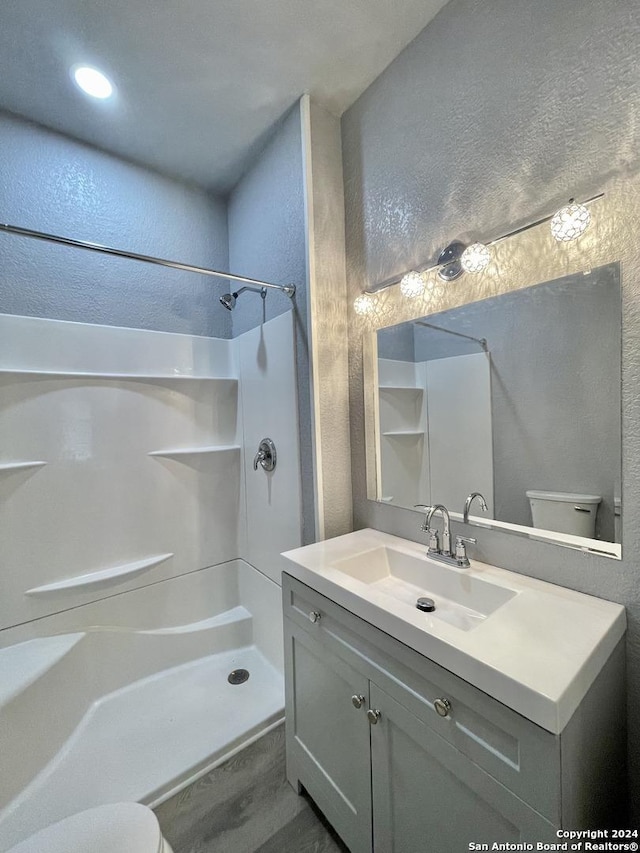 bathroom featuring toilet, vanity, and walk in shower