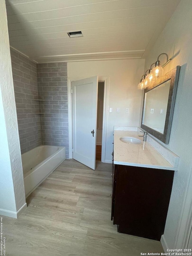 full bath featuring baseboards, a bathing tub, wood finished floors, and vanity