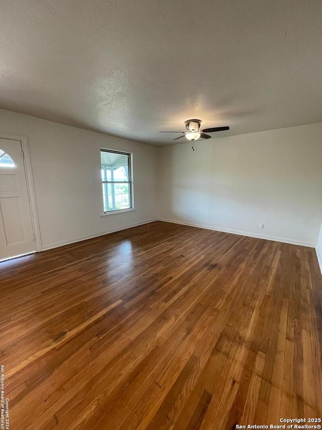 empty room with baseboards, a textured ceiling, a ceiling fan, and wood finished floors